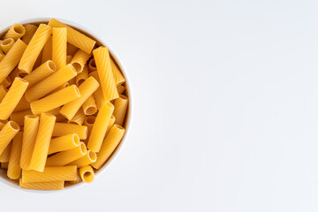 Raw dry uncooked Tortiglioni pasta spaghetti noodle on white bowl wooden background for basil tomato pesto sauce Homemade Italian food organic whole wheat vegan spaghetti for a healthy meal