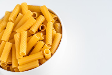 Raw dry uncooked Tortiglioni pasta spaghetti noodle on white bowl wooden background for basil tomato pesto sauce Homemade Italian food organic whole wheat vegan spaghetti for a healthy meal