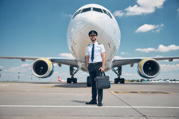 Cheerful male pilot standing outdoors in airfield © Svitlana