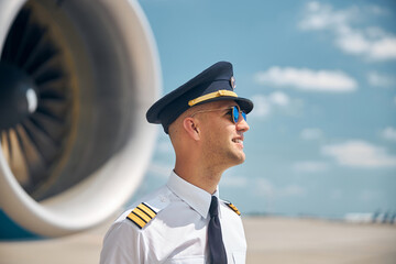 Cheerful pilot in sunglasses standing outdoors in airfield