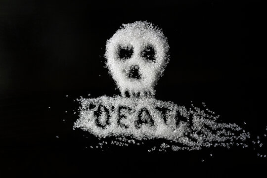 The stylized word death and the image of a skull, written in sugar on dark glass. Soft focus.