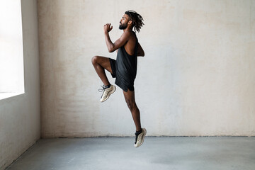 Image of handsome african american sportsman jumping while working out