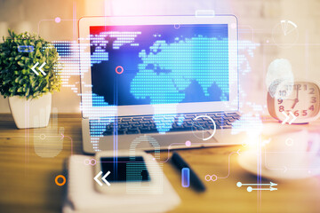 Double exposure of desktop with computer and world map hologram. International data network concept.