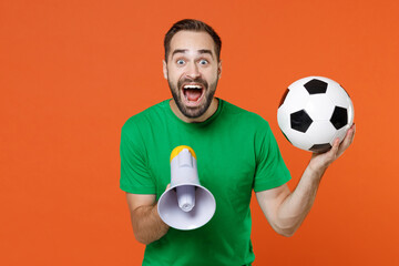 Surprised young man football fan in green t-shirt cheer up support favorite team with soccer ball...