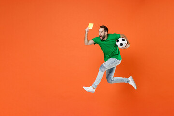 Fototapeta na wymiar Full length portrait screaming man football fan in green t-shirt support favorite team with ball jumping propose player retire from field isolated on orange background. People sport leisure concept.