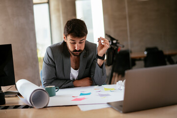 Young businessman working on projects. Handsome businessman in suit working in the office....