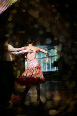 Woman dancer dancing/performing on the dance floor in colorful costume with naked back with a partner. Latin-American music and art. Motion on stage. 