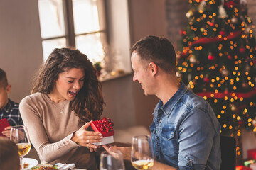 Couple exchanging Christmas presents at Christmas dinner