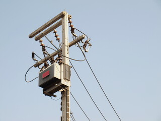 A set of fuses and wires on a pole. With a transformer in bottom view. On a blue sky background Focus close and choose the subject.