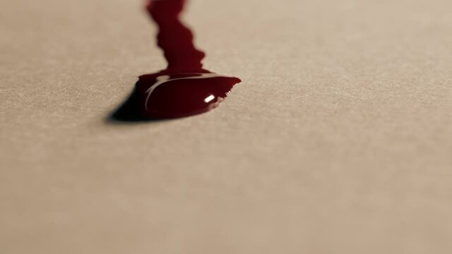 Red blood drops flows on the white paper, macro shot