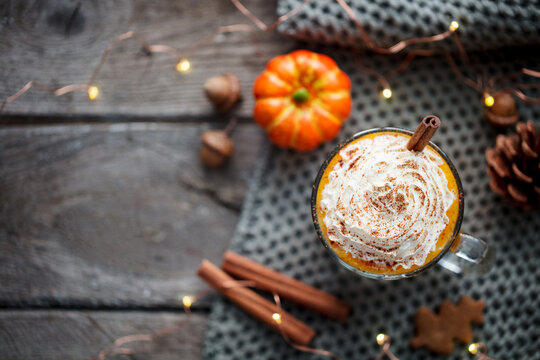 Pumpkin latte with spices. Boozy cocktail with whipped cream. Wooden background. Copy space. Top view.