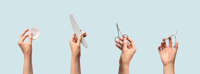 Female hands holding manicure and pedicure tools isolated on blue background with copy space, horizontal banner format. Cotton pads, nail file, scissors and cuticle nippers in human hand - obrazy, fototapety, plakaty
