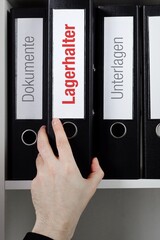 Lagerhalter. Ordner im Regal mit roter Beschriftung. Hand nimmt Dokumente aus Schrank im Büro