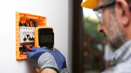Electrician at work with the tester measures the voltage in the electrical panel of a residential installation. Construction industry. Footage.