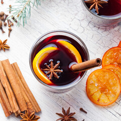 Mulled red wine with spices, orange slices on grey wooden new year and Christmas background. Close...