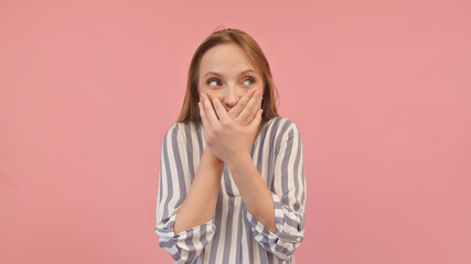 Shy young caucasian woman covering her mouth with hands. Isolated on pink background. High quality photo