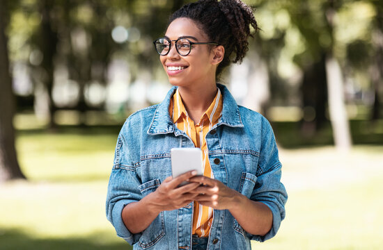African Student Girl Using Cellphone Walking On Weekend In Park