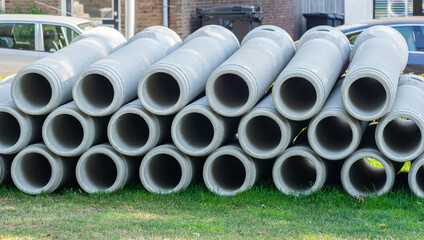 concrete prefabricated pipe networkelements lying on the ground, ready for sewerage, sewage system imrovement in big city. Infrastructure development with reinforced concrete parts.