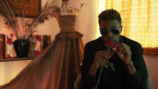 Stylish french man plucking rose petals with cold facial expression, medium shot 