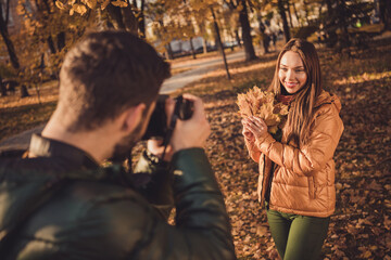 Photo of young guy taking photo digital camera his beautiful girl hold maple leaves in fall september town park
