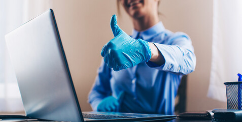 business man uses his laptop in the office, placed on the table with medical gloves and protect from Coronavirus, COVID-19
