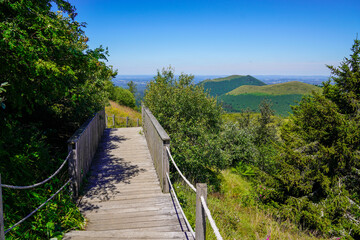 Fototapeta na wymiar wooden stairs in the forest and mountain volcano in center France puy de dome