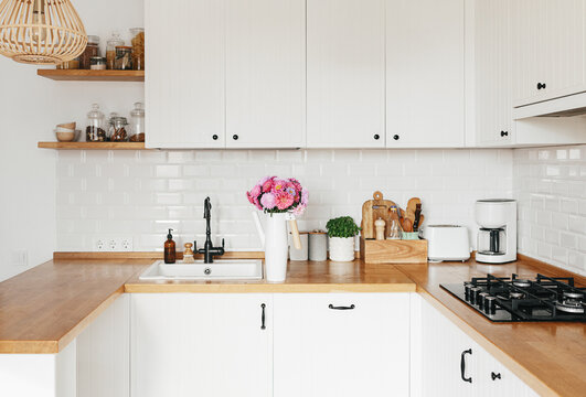 View on clean white simple modern kitchen in scandinavian style, aster Michaelmas daisy bouquet in vase on the table