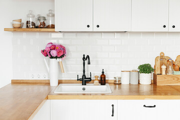 View on clean white simple modern kitchen in scandinavian style, aster Michaelmas daisy bouquet in...