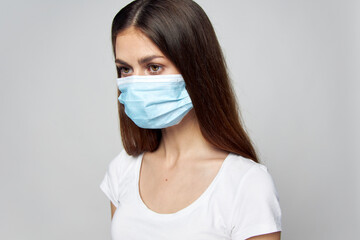 Brunette medical mask looks to the side of a white T-shirt 