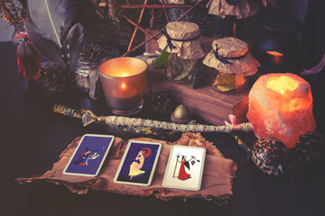 3 Tarot cards spread lying on a black table with magic items. Toned to cold colors in shadows.
