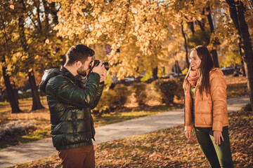 Photo of professional photographer guy take photo of beautiful girl posing in fall october town park