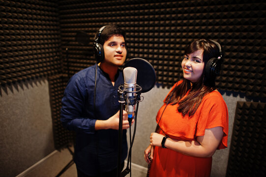 Young Asian Duet Singers With Microphone Recording Song In Record Music Studio.