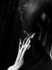 hands holding a cigarette with billowing smoke. depressed people holding cigarettes and being alone