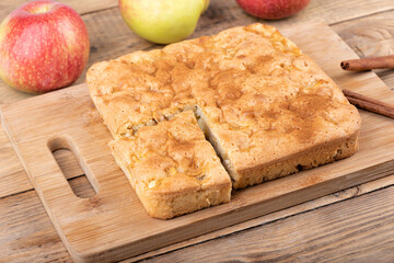Apple pie with a cut piece on a cutting board.
