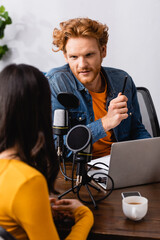 back view of brunette woman near young redhead interviewer in radio studio