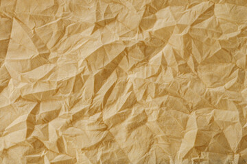 Fototapeta premium The texture of a crumpled yellow-gold disposable textile napkin.