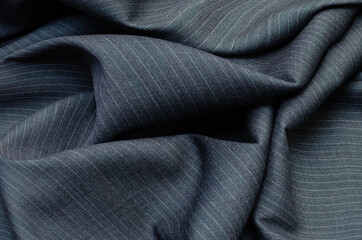 Close up of pinstriped fabric texture for garment manufacturing in dark grey color. Wool textile...