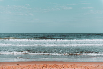 Sunset at the beach with clouds spread in the sky and calm waves of water of the ocean in the background