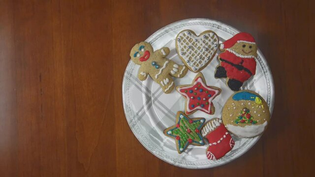 Porcelain plate full of ginger cookies on a wooden table. Every one second, one by one, cookies are disappearing. Last cake is a star figure.
