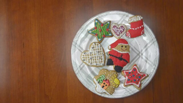 Porcelain plate full of gingerbread cookies on a wooden table. Every one second, one by one, cookies are disappearing. Last cake is a Santa Claus figure.