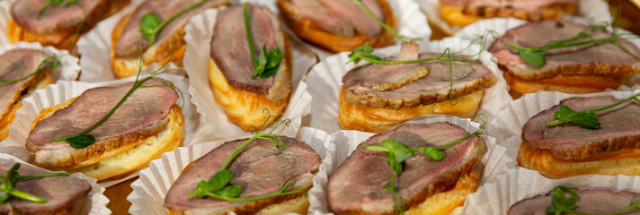 Canapes with meat and herbs. Festive table setting. Panorama format. Close-up.
