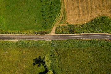 Drone photograph with new asphalt road crossing a beautiful hilly landscape in summer season