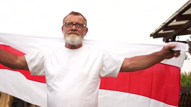 Elections 2020 and protest in Belarus. A mature man with a gray beard and glasses holds a Belarusian red-white flag, the situation in Belarus