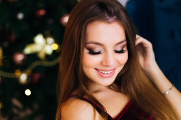 Beautiful happy woman portrait with earrings, light dark christmas backdrop. Bright makeup.