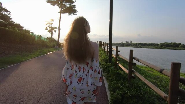 Blonde woman walks along river in summer
