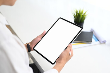 Cropped shot of businessman hands using tablet mockup with white screen at the white office desk.