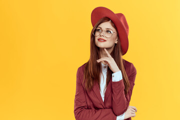 woman in red hat jacket glasses yellow background cosmetics