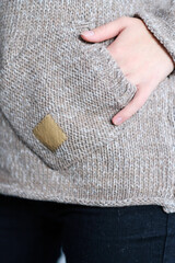 Hand in pocket. Close-up fashionable gray and beige wool sweater and jeans on a female body. Concept of casual clothing.