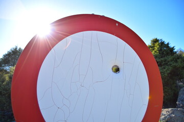 Obraz premium Road sign with bullet hole and sun background