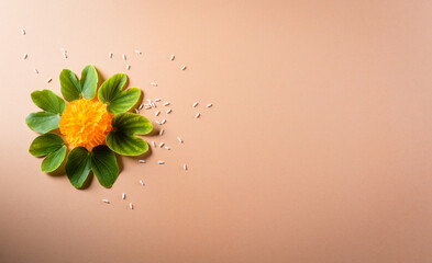 Happy Dussehra. Yellow flowers, green leaf and rice on orange pastel background. Dussehra Indian...